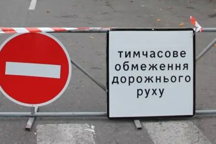 Barrier with a red no-entry sign and a white board that reads in Ukrainian 'тимчасове обмеження дорожнього руху' (temporary traffic restriction).