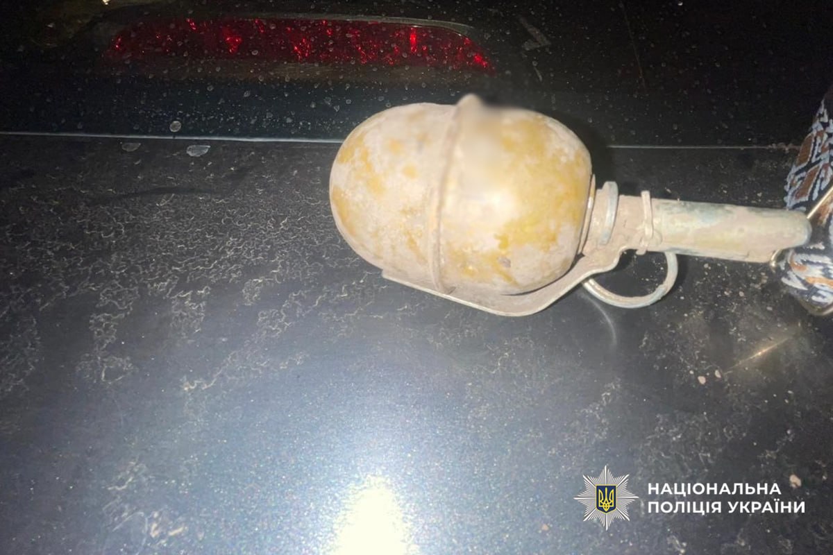Dusty hand grenade with safety lever resting on a dark surface; police watermark bottom right.