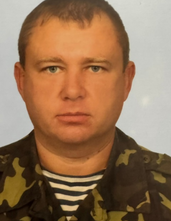 Head-and-shoulders portrait of a man in woodland camouflage uniform looking at the camera.