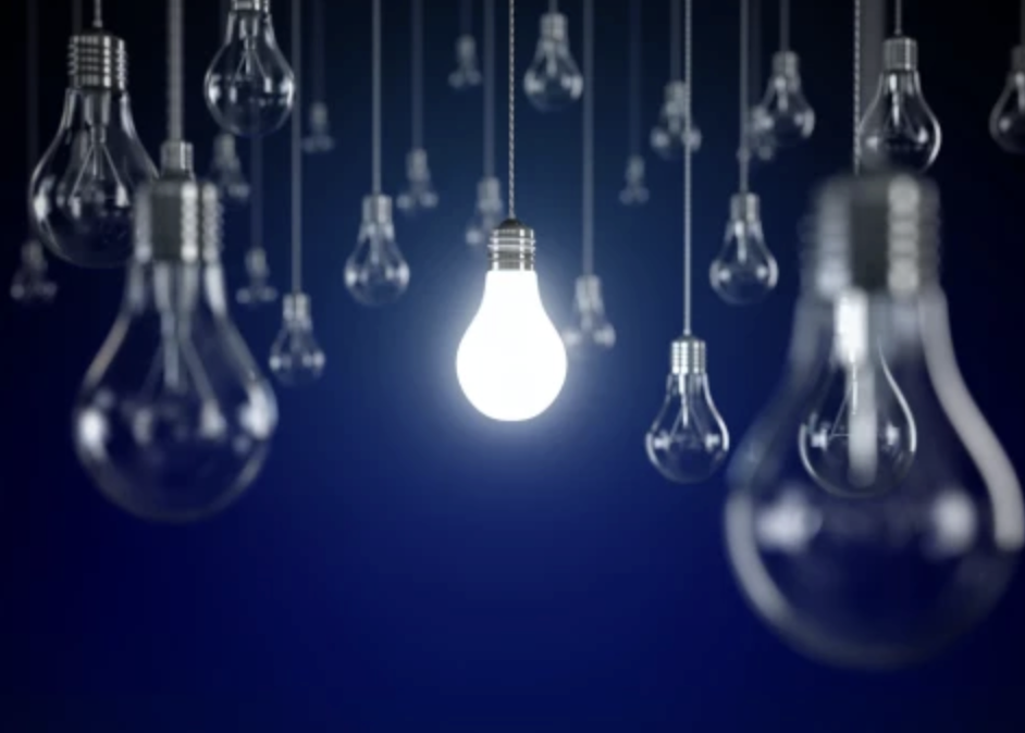 A space filled with hanging light bulbs, a single bulb glowing to symbolize a bright idea.