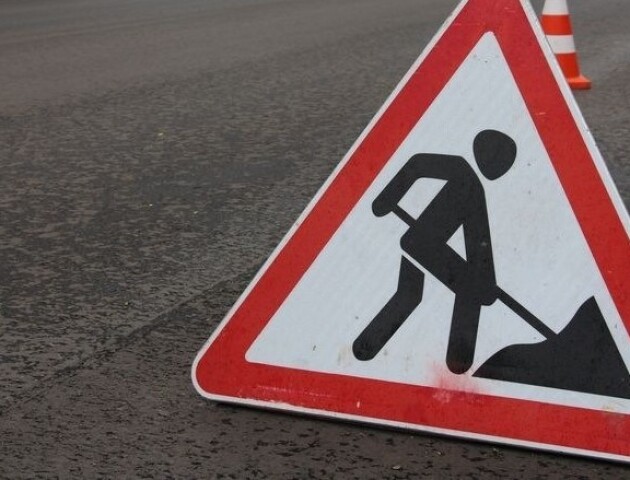 Triangular road work sign with a figure digging on a street, indicating construction ahead.