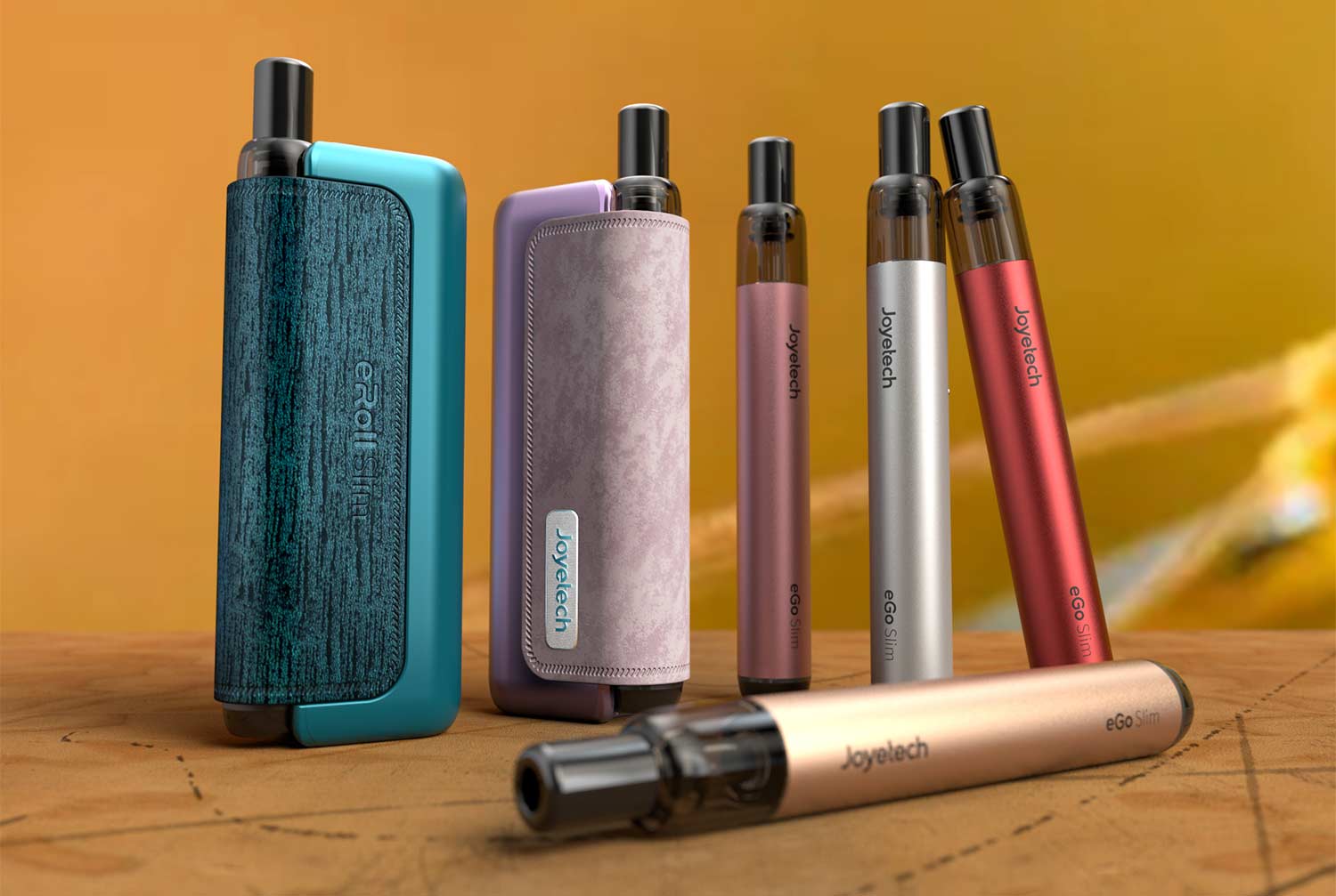 Row of colorful Joyetech e-cigarette devices standing upright on a wooden table against a warm orange backdrop.