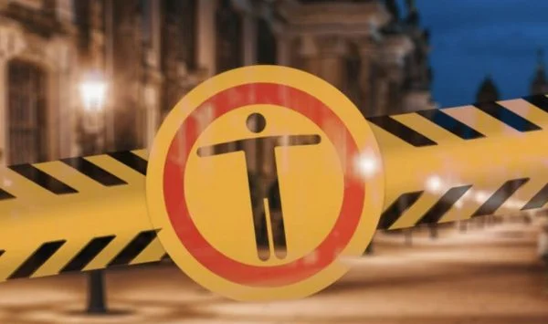 Nighttime street scene with a yellow barrier and black-and-yellow caution tape, featuring a red circled 'no entry' symbol indicating restricted access.