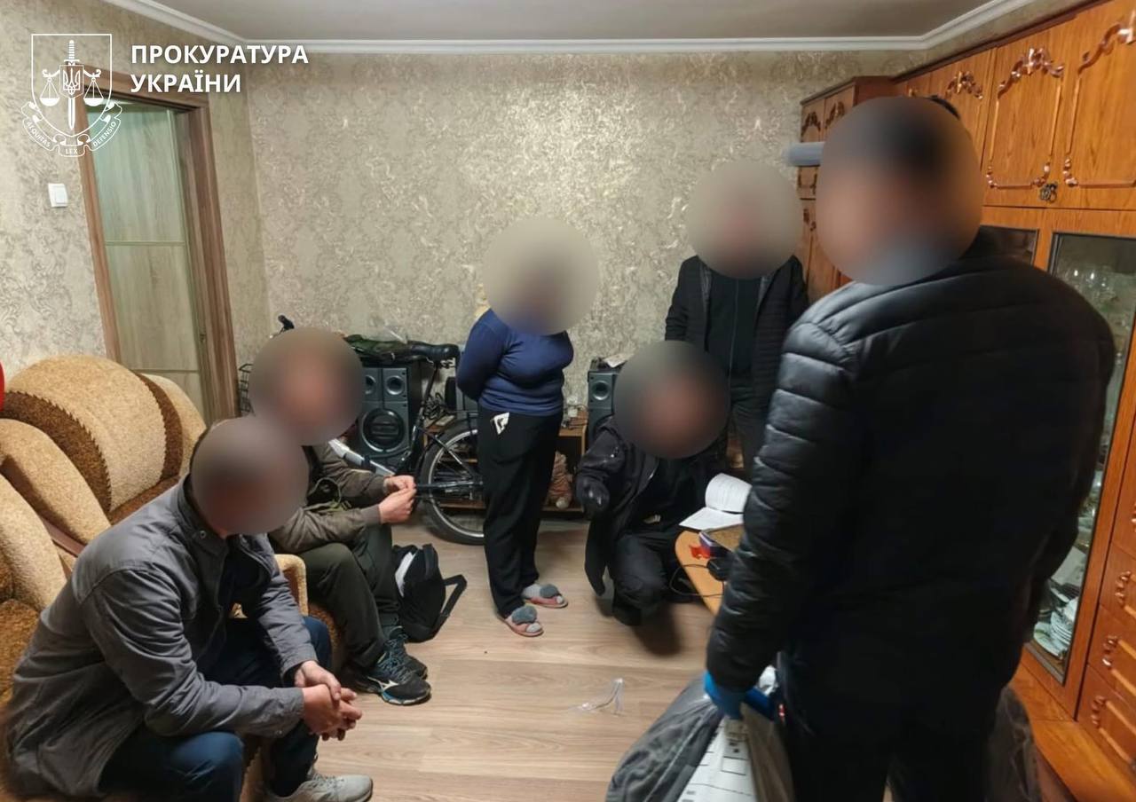 Investigation team with blurred faces gathers in a living room, Ukrainian Prosecutor's Office logo visible in the corner.