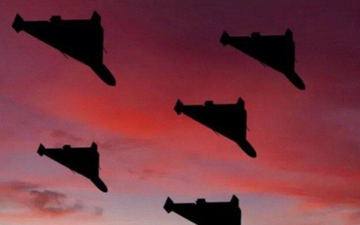 Five black jet silhouettes flying in formation across a pink-orange sunset sky.