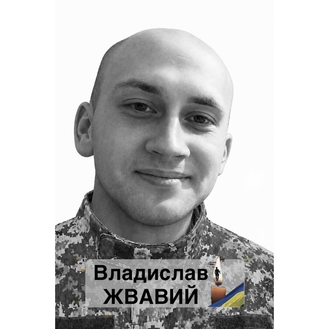 Portrait of a smiling man in camouflage military uniform; name badge reads Владислав ЖВАВІЙ with a Ukrainian flag emblem.